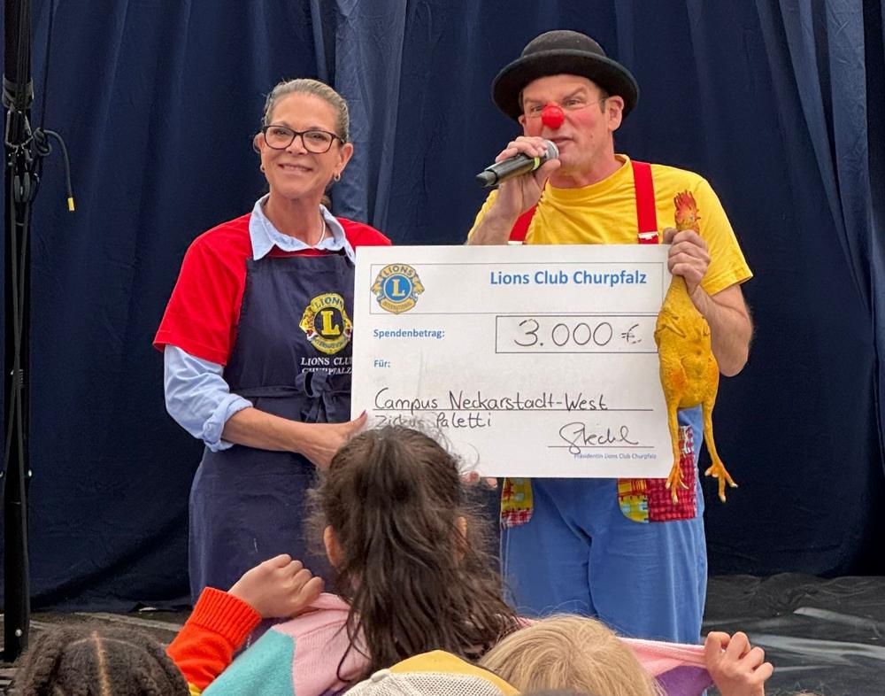 Scheckübergabe beim Kinderfest 2025. Lions Churpfalz Präsidentin Sabine Stechl (links) mit Thilo Bender, Geschäftsführer Zirkus Paletti (rechts)